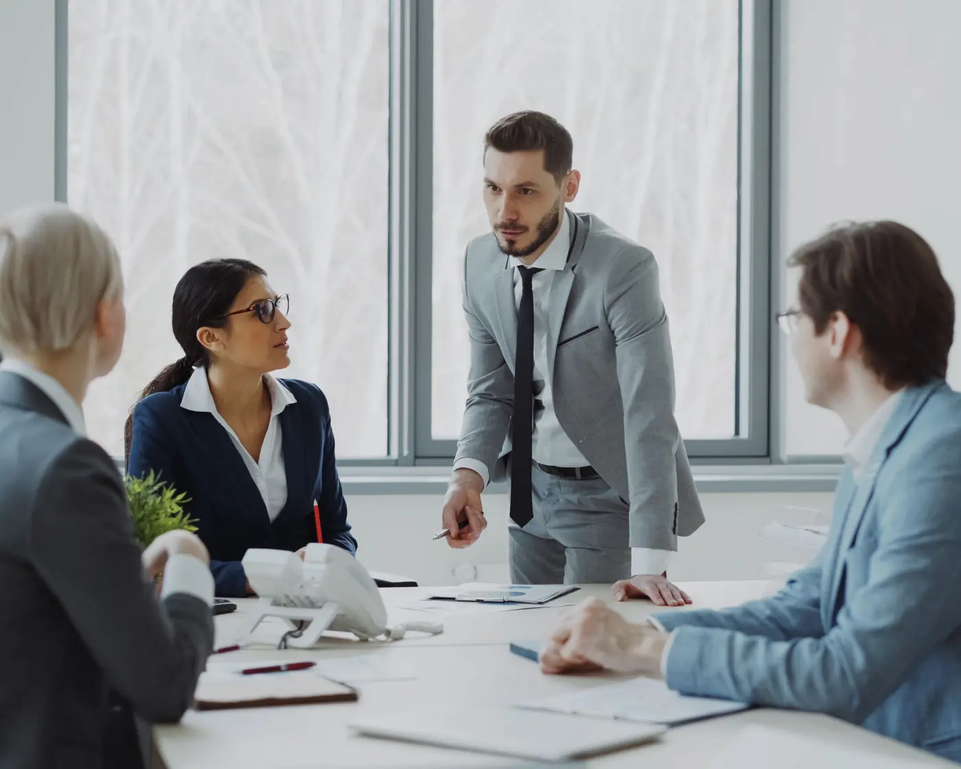 A project team in a boardroom meeting, with one colleague presenting to the others.