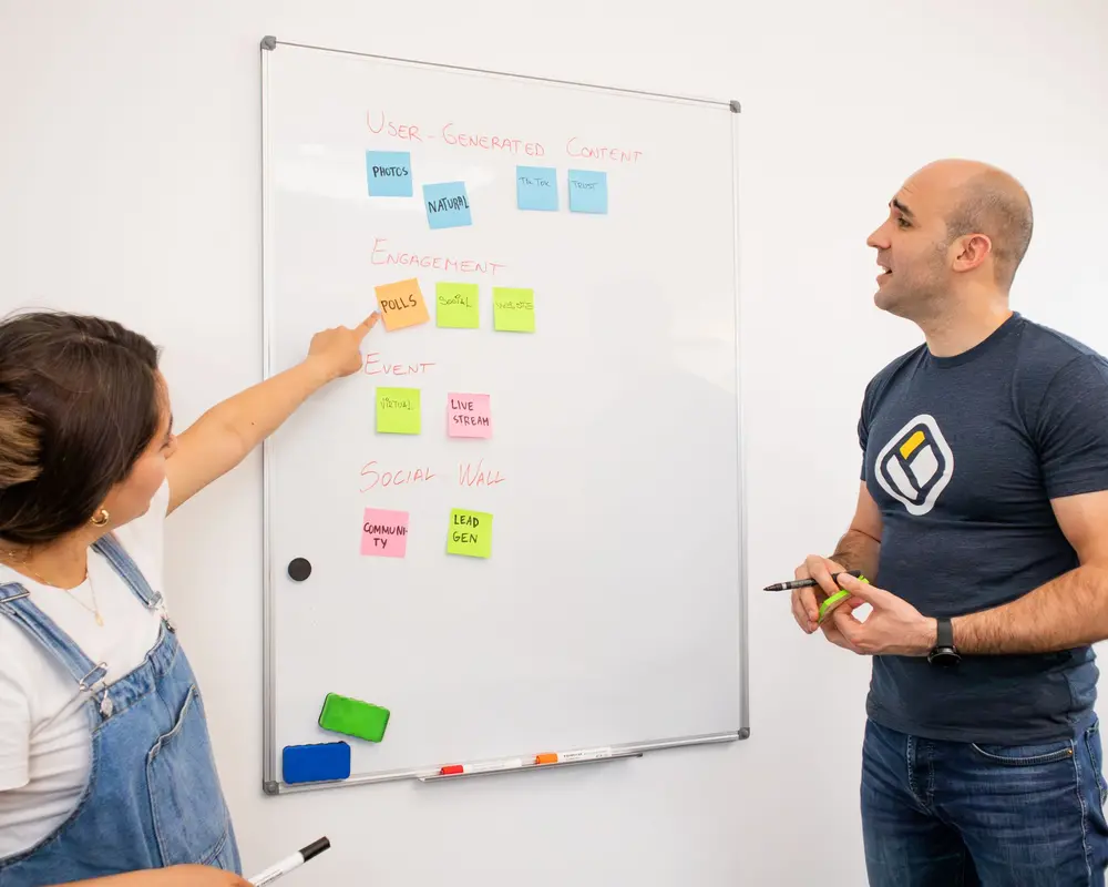 Two colleagues planning project stages on a whiteboard.